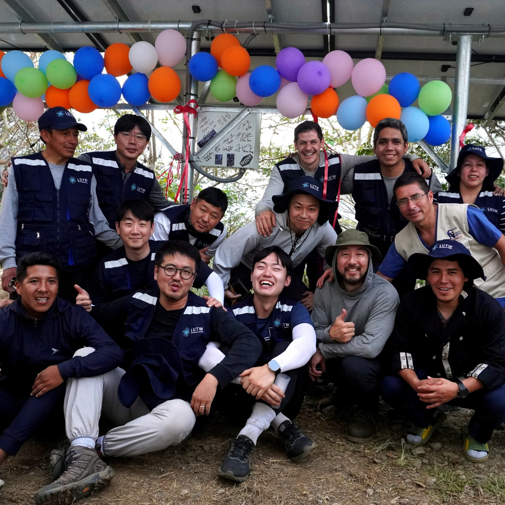 LUTW volunteers and project team members posing together under a the clinics new solar array to celebrate the Ccorimayo health center solar and internet charity project.