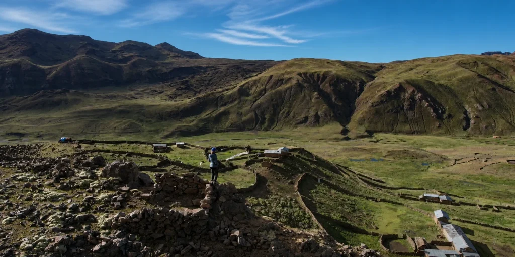 A LUTW volunteer looking out over a rural community and andean valley in Peru under a clear blue sky.