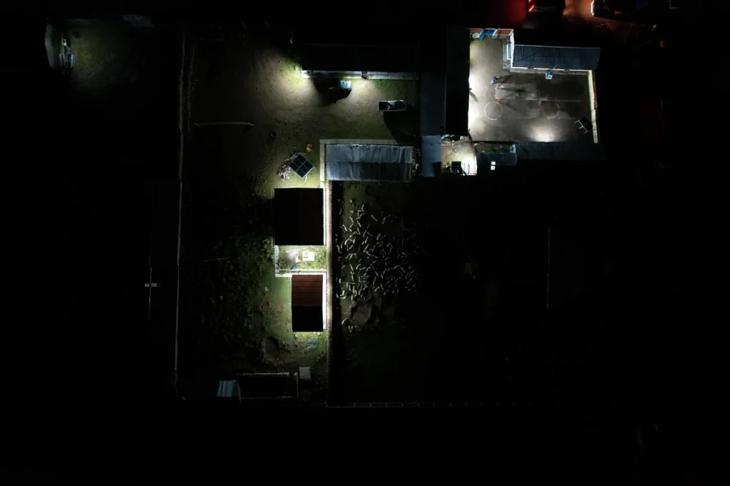 An aerial drone view at night showing illuminated buildings and courtyards at the Pedregal school, powered by a recently installed NAIT solar energy system.