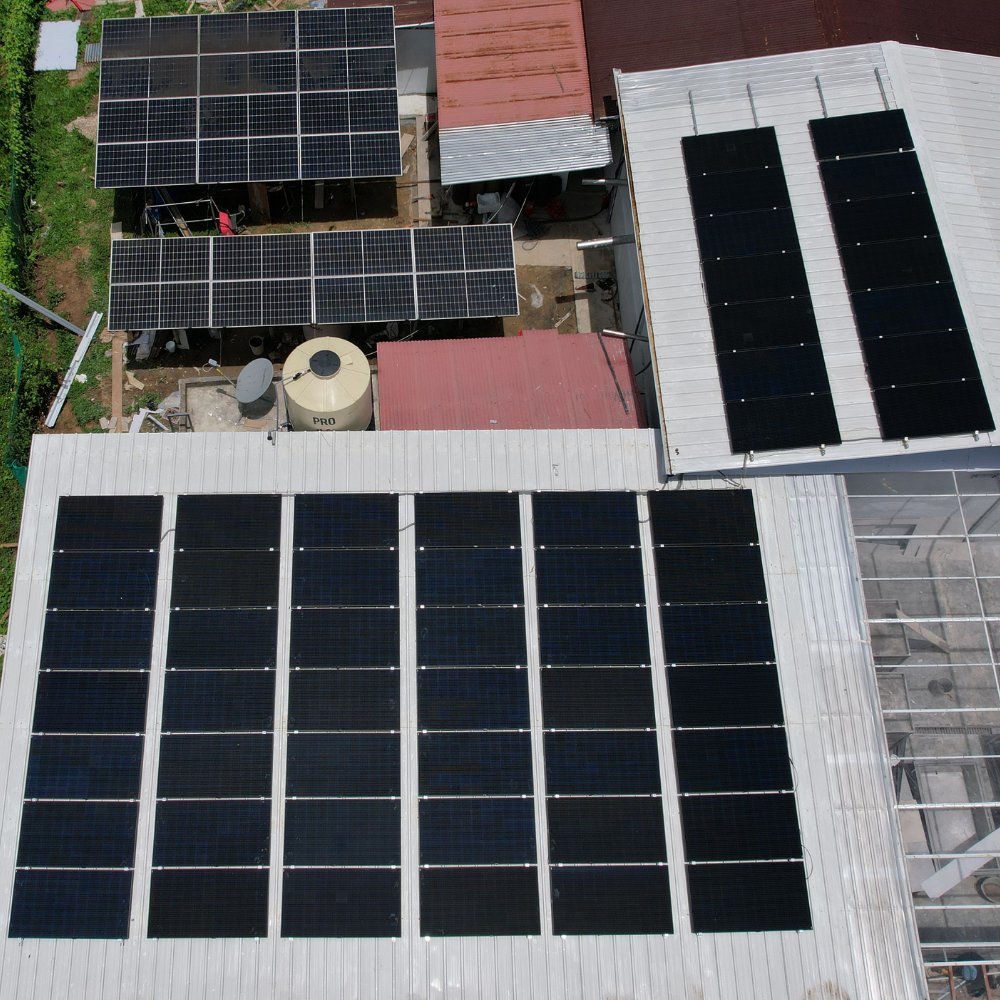 An aerial drone view showing multiple arrays of solar panels installed on the roofs of a facility in the community of Soledad, a joint renewable energy project by Terra Nuova and LUTW.